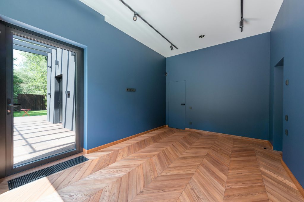 Contemporary interior room with blue walls, wooden flooring, and large glass door.